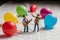 Two miniature figurines in a festive scene of music and balloons