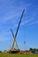 Two mobile cranes with yellow arrows lift a heavy load against the blue sky, construction of an industrial facility, houses, build