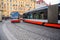 Two modern electric trams passing each other as they round a corner on the cobbled streets of the old town district of Prague