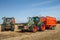 Two Modern Fendt tractors pulling orange trailers