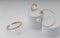 Two modern golden bracelets and golden ring on white paper setup