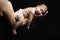 Two months years old little newborn baby resting on her mothers arm in front of dark background