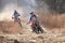 Two motorbikes kicking up trail of dust on sand track during ral