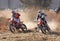 Two motorbikes kicking up trail of dust on sand track during ral