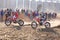 Two motorbikes kicking up trail of dust on sand track during ral