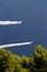 Two motorboats against a blue sea and trees