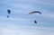 Two motorized paragliders flying in blue sky