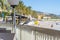 Two mottled pigeons stand on a cafe railing overlooking the beach and sea in the Mediterranean town of Menton, France.