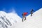 Two mountain backpackers walking on steep hill with snowed peaks background, Himalayas