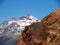 Two mountains brown and snowy with blue sky in the background