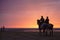 Two mounted Guardia Civil police officers patrolling beach at sunset