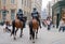 Two mounted policemen patrol the street in center