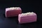 Two mousse desserts with almond biscuit, strawberry coolie and strawberry mousse covered gourmet pink chocolate glaze on