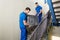 Two Movers Carrying Furniture On Staircase