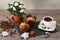 Two muffins, cup of aroma coffee, coffee grains and flowers of azalia on gray wooden background.