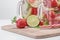 Two mugs of fruit water with strawberries mint, lemon and lime stand on a wooden stand next to fresh strawberries, lime and mint,