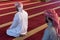 Two muliethnic religious muslim young people  praying and reading Koran together. Group of muslims praying in the mosque