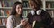 Two multi ethnic students standing in college library with smartphone