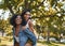 Two multiethnic female best friends having fun and playing in the park - two friends giving eachother a piggy back and
