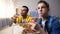 Two multiethnic male teenagers eating pizza and watching TV show, leisure time