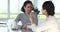 Two multiethnic women sit at table holding mugs enjoy talk