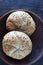 Two multigrain buns with sesame seeds and flaxseed on a brown plate