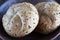 Two multigrain buns with sesame seeds and flaxseed on a brown plate