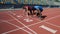 Two multiracial athletes in starting position, ready to run after command