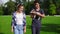 Two multiracial friends walking on the green grass in park enjoying the day while holding cute little jack russell