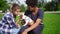 Two multiracial young friends sitting on the green grass in park enjoying the day while holding cute little jack russell
