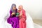 Two Muslim girls exchange money envelope gifts to celebrate end of Ramadan, dressed in red and purple kebaya traditional dress,