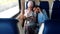 Two Muslim women traveling by train, one woman reads, another talking on the phone