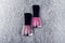 Two nail polish bottles on silver background. Pink fingernail varnish top view on fabric texture backdrop, folded lines