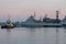 Two naval harbor tugs against the background of warships in the Petrovskaya pier of Kronstadt. Evening sunset. Russia