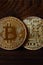 Two new golden physical bitcoins lies on dark wooden backgound, close up. High resolution photo. Cryptocurrency mining concep