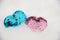 Two nice hearts decorated by blue, pink sequins laying in white winter snow