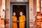 Two novices are standing reading books together in the temple.