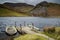 Two old boats, half filled with water are moored at a jetty on Llyn Dywarchen in the Snowdonia National Park