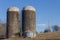 Two old concrete grain silos on a hillside, blue sky winter
