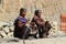 Two old elderly Nepalese women with a tanned face in wrinkles in traditional clothes are sitting and sorting out their rosary. Tr