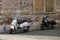 Two old fashioned motor scooters parked on the street near a brick wall with graffiti