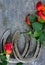 Two old horse shoes paired with silk red roses on a scratched up steel background