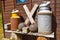 Two old milk churns and other objects on a wooden bench against the wall of a shed