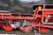 Two old red driving wheels of a steam locomotive engine with steam