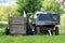 Two old rustic dilapidated wooden tractor trailers with four and two tires covered with thick nylon left in backyard surrounded