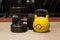 Two old and used gym black metal dumbbells with yellow kettlebell on a wooden floor.