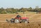 Two old vintage red tractors ploughing