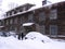 Two old women near a large wooden house talking in the winter