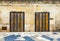 Two old wooden doors on marble brick wall. Colored tiled floor