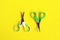 Two open baby green scissors on yellow background, flat lay with copy space. Baby care concept